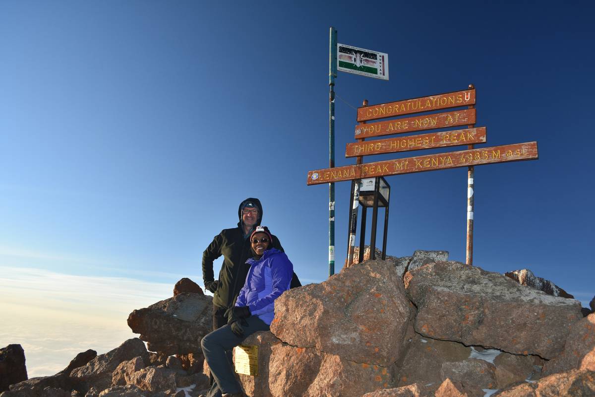 A photo of someone smiling atop a mountain during a hike, holding their 'before' picture.