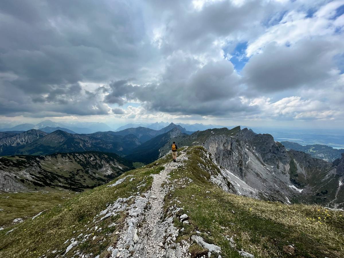 A hiker standing atop a ridge with mountains in the background