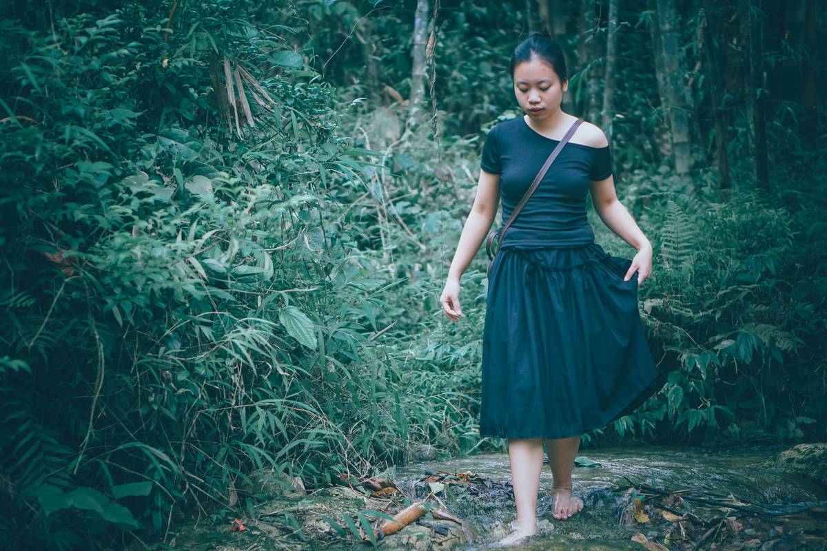 Woman smiling while hiking uphill on a forest trail during sunrise