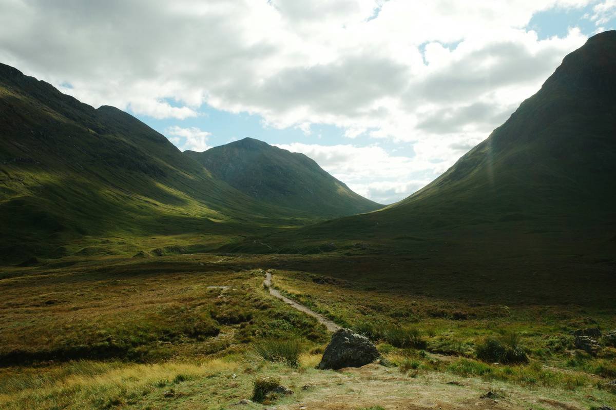 A scenic trail through lush green hills with hikers enjoying the view.
