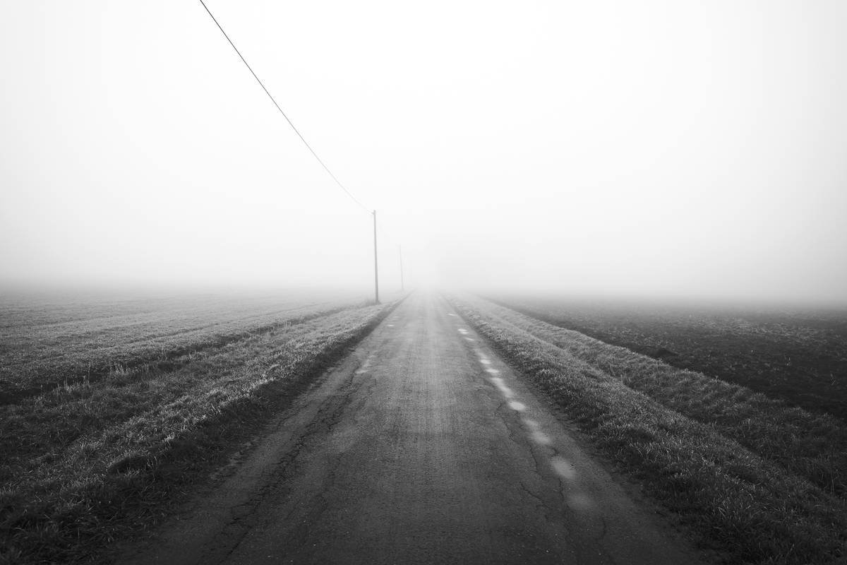 A long, empty road disappearing into fog.