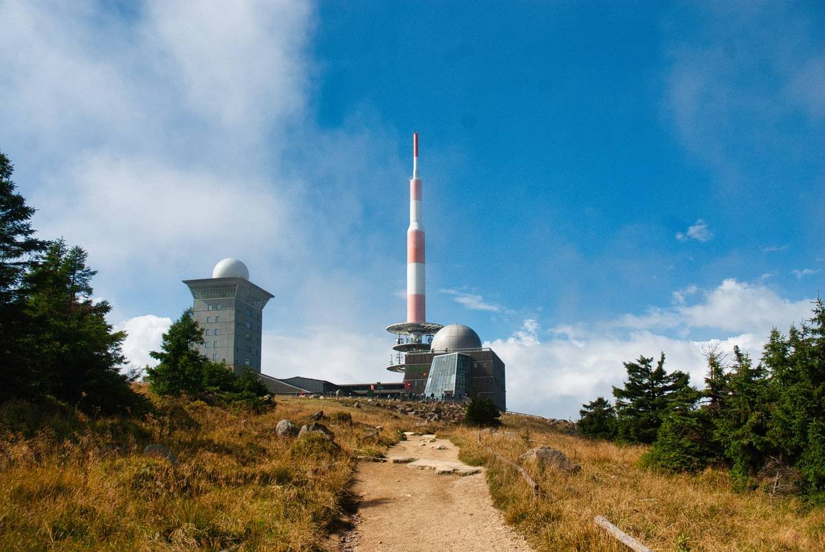 Broadcasting tower on a grassy hilltop under blue sky