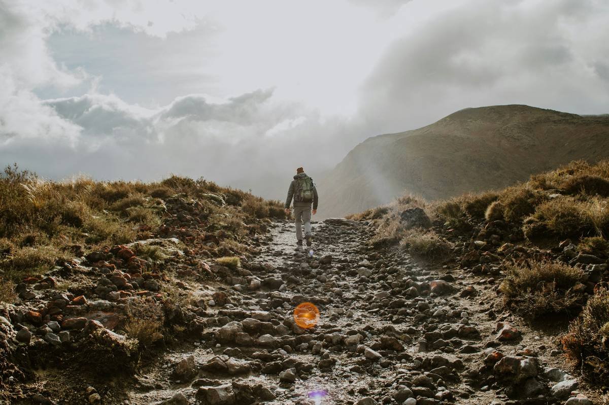 person in white shirt walking on rocky road during daytime